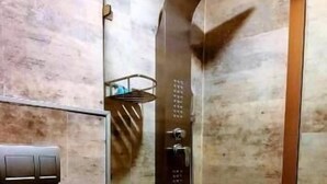 Un baño moderno con ducha de vidrio, inodoro y panel de control en la pared.
