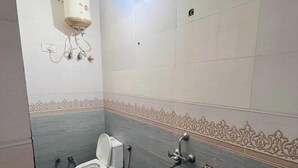 Ein Badezimmer mit Toilette, Waschbecken und einem an der Wand montierten Warmwasserbereiter.