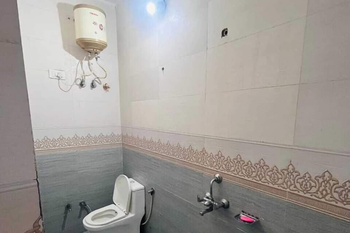 Ein Badezimmer mit Toilette, Waschbecken und einem an der Wand montierten Warmwasserbereiter.