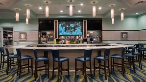 Un espace bar doté d’un îlot central, de tabourets de bar et d’un écran de télévision diffusant des images du monde sous-marin.