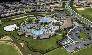 An aerial view of a residential area with a swimming pool complex, roads, and parked cars. - Last Minute Disney Getaway! Private Pool, Hot Tub & Game Room. Book Now! #14244 (Orlando)