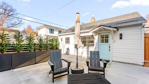 A patio with two chairs and a table, an umbrella, and a house in the background. - The Hydeaway at Hyde Park (Boise)