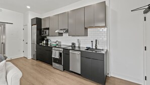 Een moderne keuken met donkere kastjes, een roestvrijstalen koelkast, een magnetron, een fornuis en een vaatwasser.