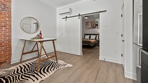Een modern interieur met een rug in zebraprint, een ronde spiegel, een witte deur en een bed met kussens.