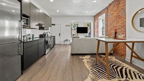 Een moderne keuken met roestvrijstalen apparatuur, een vloerkleed met zebraprint en een bakstenen muur.