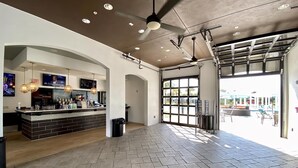 A spacious lobby with a bar area, ceiling fans, and large windows allowing natural light. - Last Minute Disney Getaway! Villa with Private Pool & Hot Tub. Book Now! #18234 (Orlando)