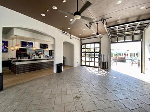 A spacious lobby with a bar area, ceiling fans, and large windows allowing natural light. - Last Minute Disney Getaway! Villa with Private Pool & Hot Tub. Book Now! #18234 (Orlando)