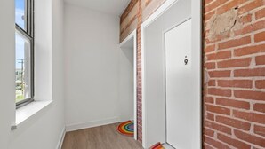 Ein schmales Gang mit einem Fenster, einer weißen Tür und einer Ziegelwand.