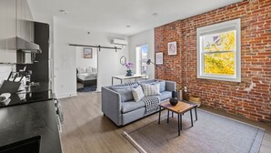 Ein modernes Wohnzimmer mit grauem Sofa, Couchtisch und Backsteinwand.