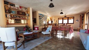 Amplia sala de estar con comedor, muebles de madera y una estantería llena de libros y objetos decorativos.