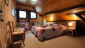 Un dormitorio acogedor con techo de madera, una cama con colcha, una mesita de noche con lámpara y una silla.