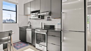 Una cocina moderna con gabinetes grises, electrodomésticos de acero inoxidable, microondas integrado y lavavajillas.