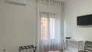 A bedroom with a bed, a desk, a chair, a TV, and an air conditioning unit. - Just minutes from Ogliastra's most beautiful beaches, rooms with en suite facilities (Cardedu)