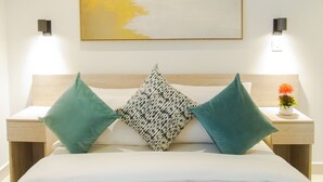 A neatly arranged hotel room with a large bed, two bedside tables, a wall-mounted artwork, and a small potted plant. - Comfy One Bed Room Apartment at Lennox (Accra)