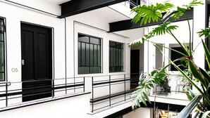 Un edificio moderno con fachada blanca, ventanas de marco negro y un balcón con macetas.