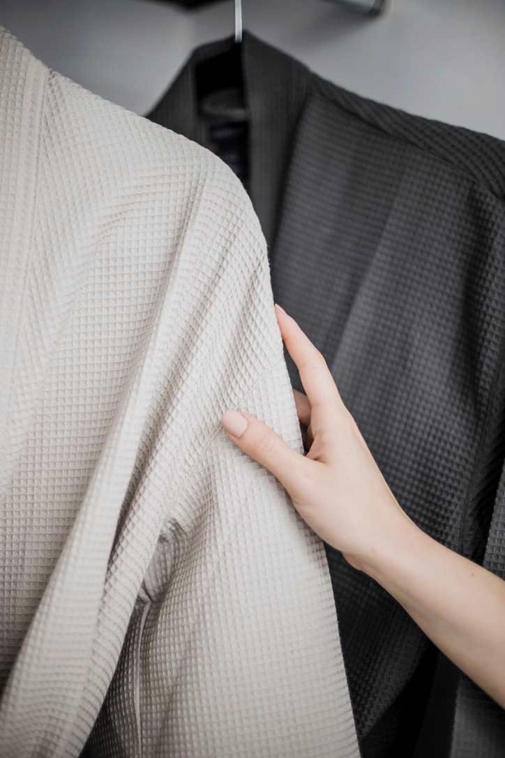 Un gros plan d’un tissu texturé, peut-être une couverture ou un vêtement, qu’une main effleure délicatement.