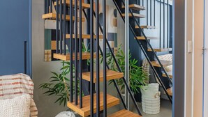 Ein modernes Interieur mit einer Holztreppe, einem Sofa und einer Pflanze.