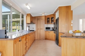 A modern kitchen with wooden cabinets, a stainless steel sink, and a microwave.