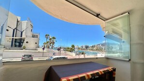 Ein Balkon mit Tisch und Stühlen mit Blick auf Strand und Stadtbild.