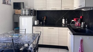 Una cucina moderna con mobili in legno chiaro, un piano di lavoro nero, un forno a microonde, un tostapane e una macchina da caffè.