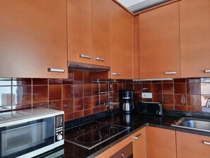 Eine Küche mit braunen Schränken, einer Mikrowelle, einem Herd, einer Kaffeemaschine und einem Toaster.