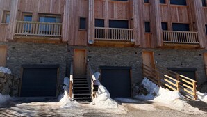 A multi-story wooden building with balconies, a stone facade, and a snow-covered ground. - New chalet in Vars, 10 guests, 300m from slopes (Vars)