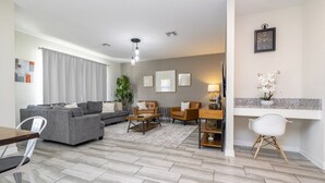 Un salon moderne avec un canapé gris, une table basse en bois et un coin repas comprenant une chaise blanche et une table.