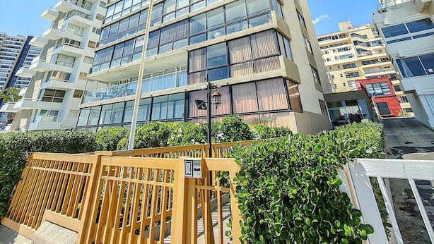 Un immeuble à plusieurs étages doté de balcons, de grandes fenêtres et d’une entrée sécurisée par un portail.