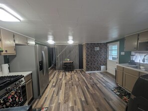 A kitchen with a central island, a refrigerator, and a stove. - Wooden Oasis minutes from Burdette & USI (Evansville)