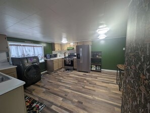 Eine kleine Küche mit Waschmaschine, Kühlschrank und Mikrowelle.