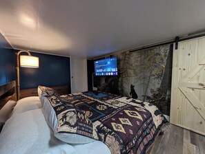 Ein Schlafzimmer mit einem Bett, einem an der Wand befestigten Fernseher und einem Holzschrank.