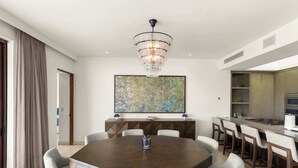 Un espace de salle à manger moderne avec une table ronde, des chaises, un lustre et un grand tableau abstrait.