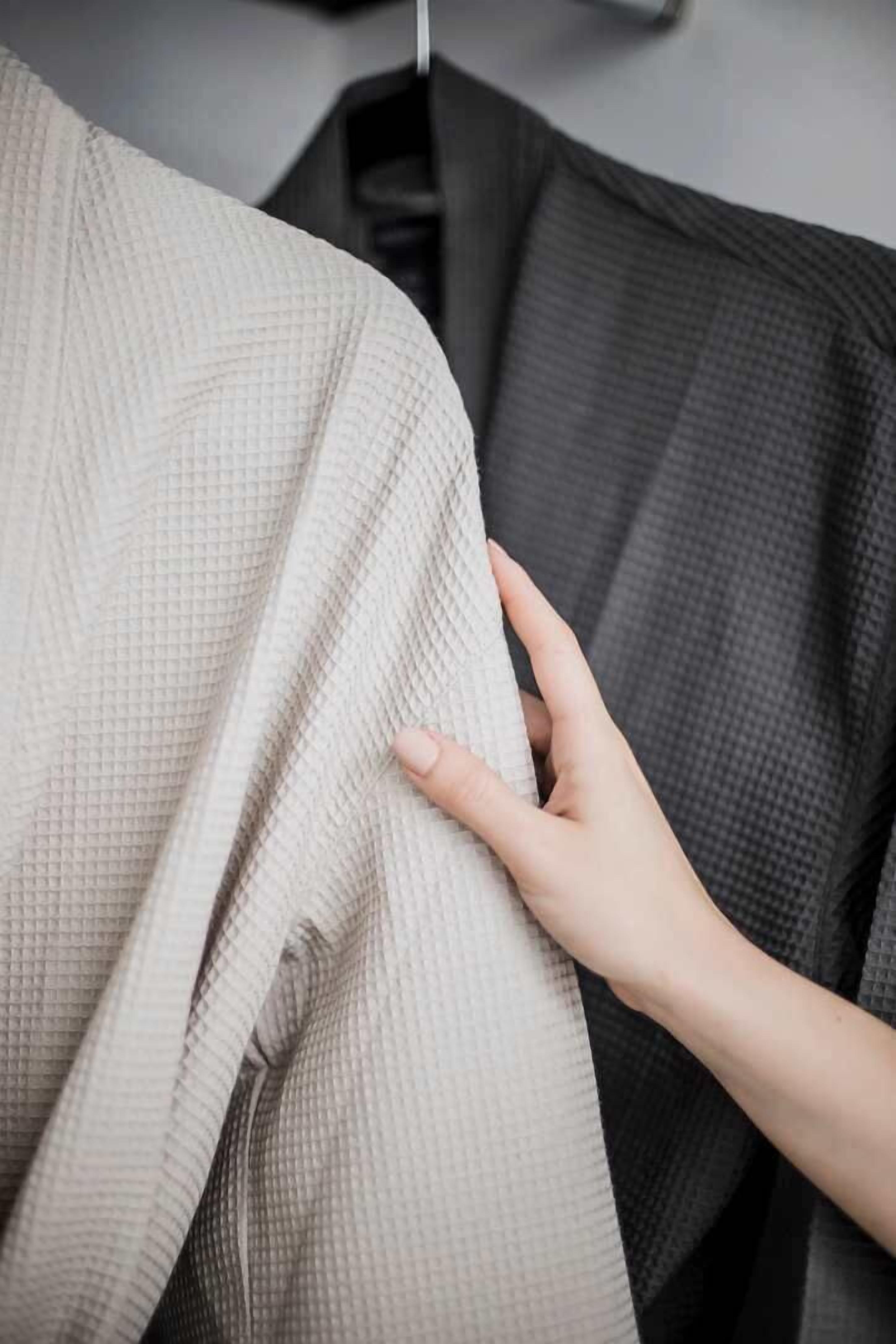 A close-up of a textured fabric, possibly a blanket or a piece of clothing, with a hand gently touching it.