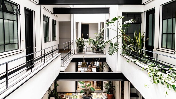 A multi-level interior with balconies, potted plants, and a central open space. - Puerta roja Increible ubicacion en condesa suite (Ciudad de México)