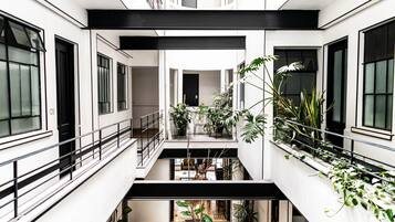 Un interior de varios niveles con balcones, plantas en macetas y un espacio central abierto.