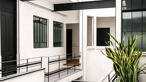 Een modern gebouw met witte muren, zwarte hekken en grote ramen.