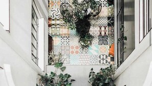 Een modern interieur met een geometrisch vloerpatroon, witte muren en verschillende potplanten.