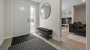 A modern entryway with a bench, a coat rack, and a large mirror. - Le Relais Mont-Blanc (Les Laurentides)