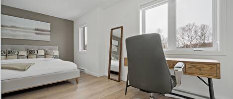 Ein Schlafzimmer mit einem Bett, einem Schreibtisch und einem großen Fenster.
