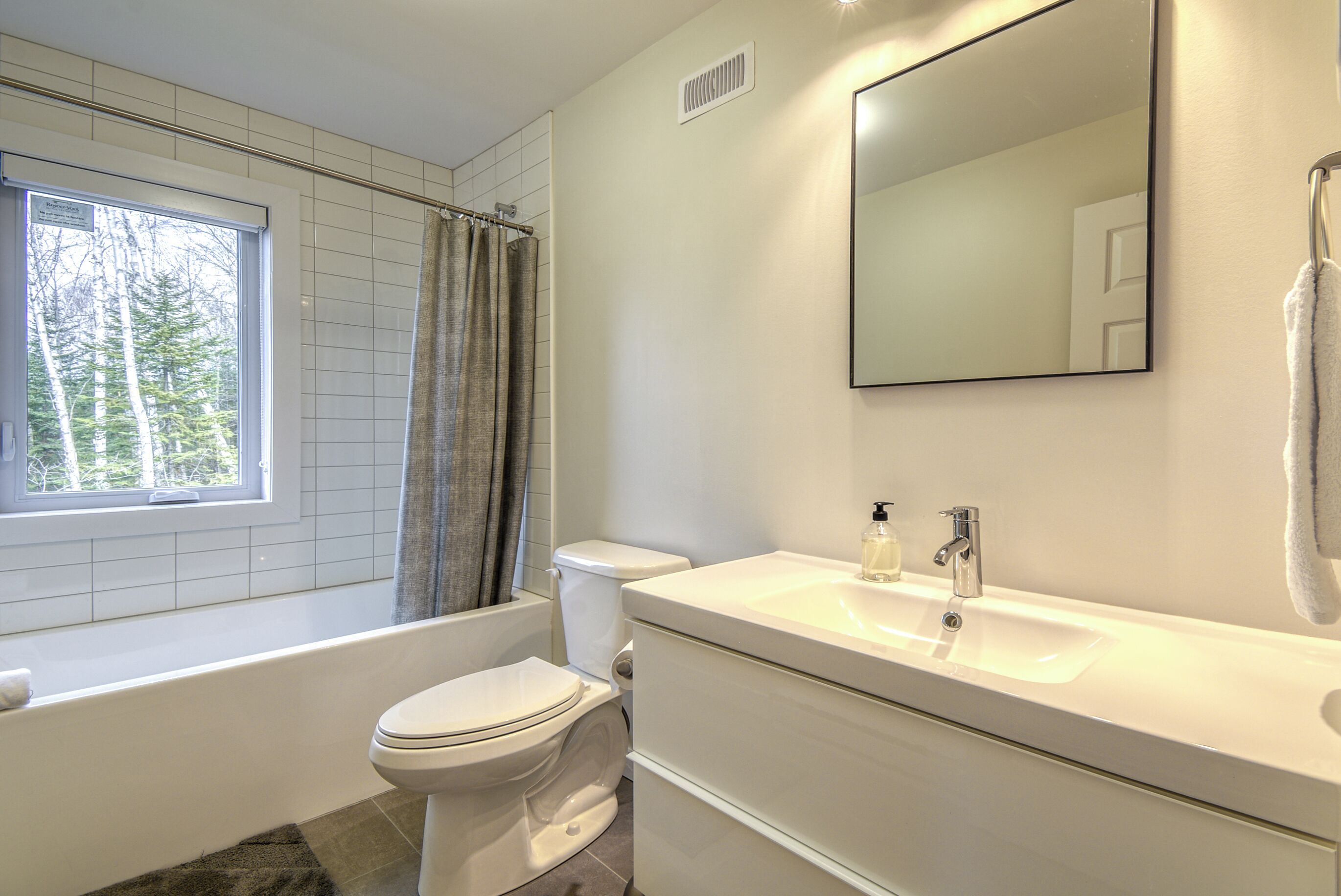 Une salle de bain moderne équipée d’une baignoire, de toilettes et d’un lavabo.
