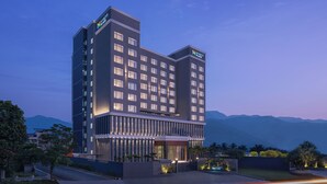 Et moderne hotel med flere etager, med en markant indgang og udsigt over det omkringliggende landskab.