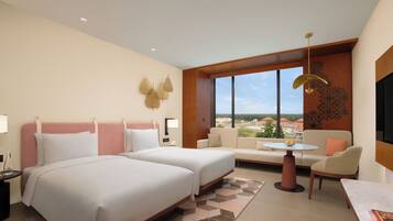 A hotel room with two beds, a sofa, a small table, and a TV.