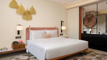 Une chambre d’hôtel avec un grand lit, deux tables de chevet, une lampe fixée au mur et un élément décoratif représentant des feuilles, accroché au mur.