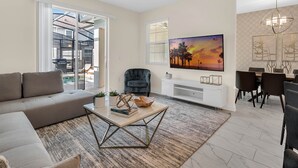 A modern living room with a sofa, coffee table, and a painting of a sunset. - Last Minute Disney Getaway! Private Pool & Themed Bedrooms. Book Now! #150581 (Orlando)