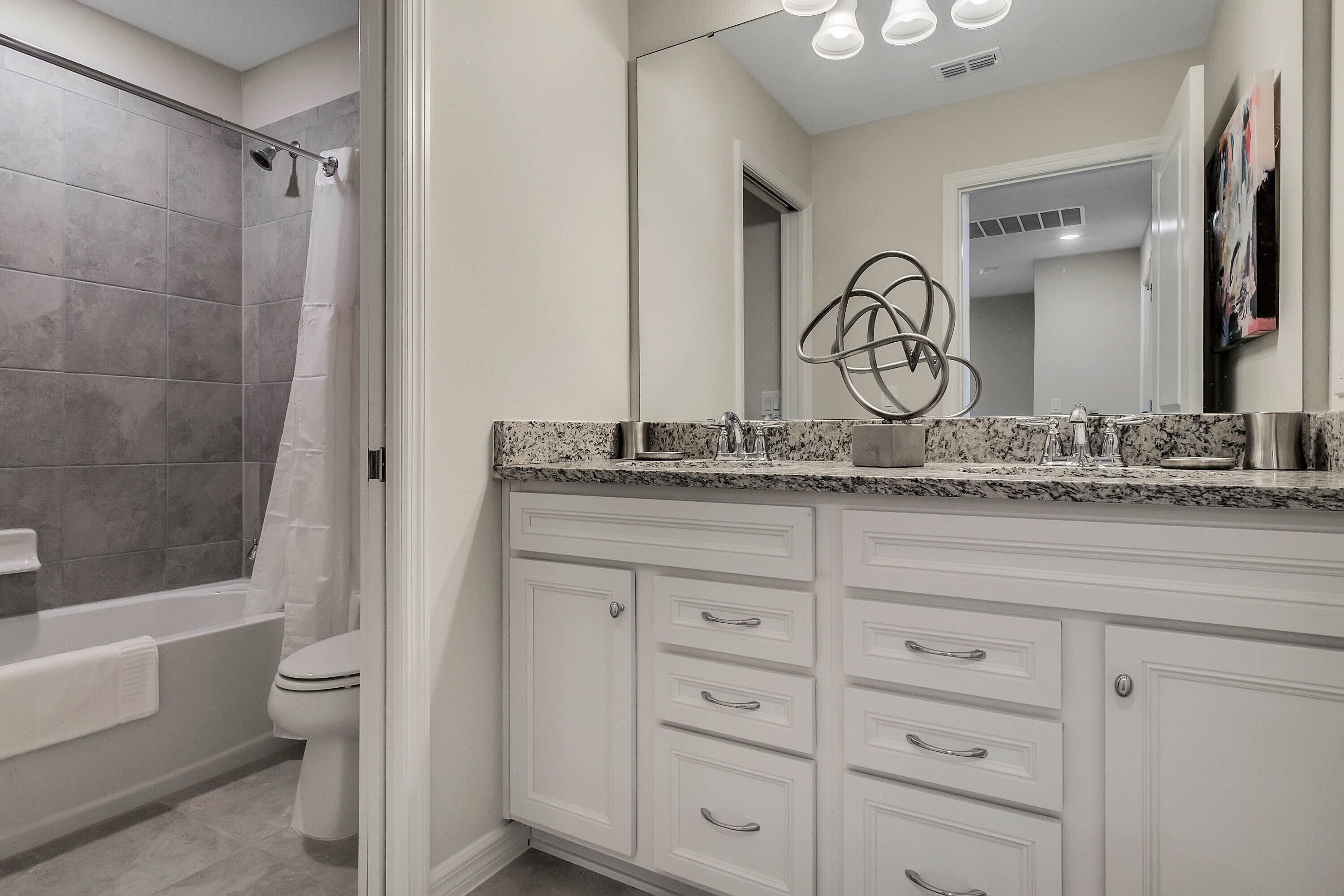 A modern bathroom with a shower, toilet, and vanity with drawers.