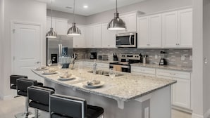 A modern kitchen with white cabinets, a granite countertop, and stainless steel appliances. - Last Minute Disney Getaway! Private Pool & Themed Bedrooms. Book Now! #150903 (Orlando)