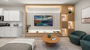 Een moderne woonkamer met een grote televisie, een houten salontafel en een zithoek met een bank en fauteuils.