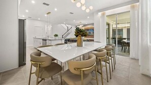 Une cuisine moderne avec un îlot central blanc, des chaises de couleur beige et un vase doré.