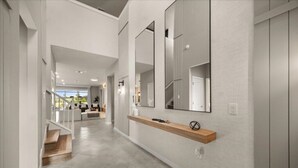 A modern hallway with a wooden shelf, large mirrors, and a staircase leading to another room. - Last Minute Disney Getaway! Private Pool, Game Room & Themed Bedrooms. Book Now! #138731 (Orlando)