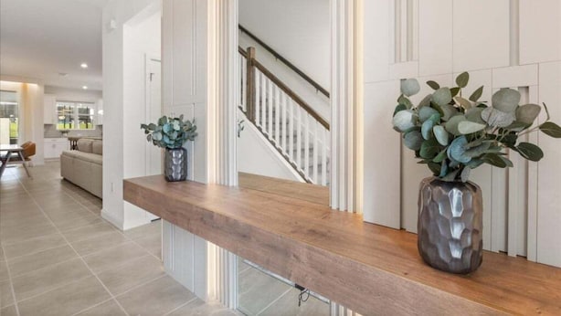 Ein modernes Interieur mit einer hölzernen Bank, einer Treppe und zwei Zimmerpflanzen.